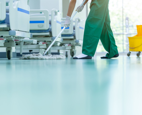 Side view of man with socks on mopping epoxy floor, hospital