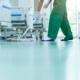 Side view of man with socks on mopping epoxy floor, hospital